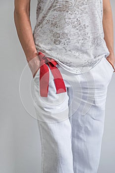 Front crop view of young fashionable woman dressed with white lien pants, t shirt and a red belt