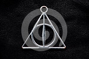 Front Deathly Hallows necklace on a black background of fabric texture
