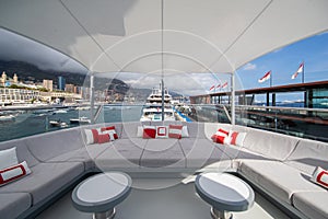 The front deck of huge yacht in port of Monaco at sunny day, landmarks of Monte-Carlo and a lot of motorboats are on