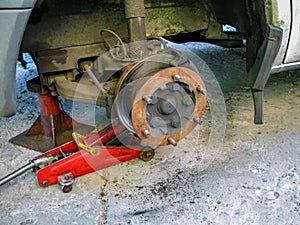 Front disc brake on car in process of new tire replacement