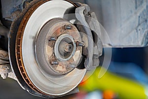 Front disc brake on car in process of service. The rim is removed showing the front rotor and caliper