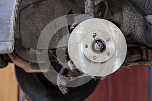 Front disk brake on car in process of damaged tyre replacement.