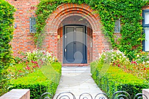 Front door of an English cottage decorated with garden plants and flowers