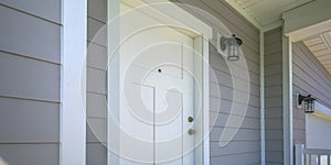 Front door of a home with a lamp on the gray wall