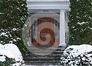 front door of house with snow covered shrubbery
