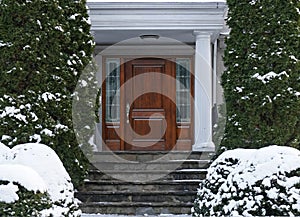 front door of house with snow covered shrubbery photo