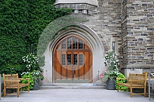 Front door with leaded glass and ivy covered stone wall of gothic style college building