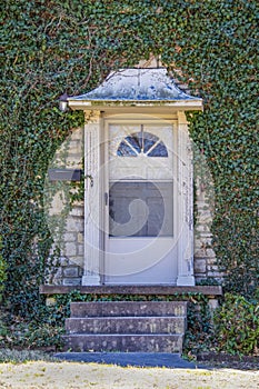 Front door with metal awning - old and worn but beautiful - set in ivy covered rock house - Close-up of entrance