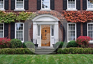 Front door of old brick house surrounded by ivy in autumn