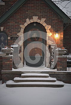 Front door and snow covered porch of idyllic home at the holidays.