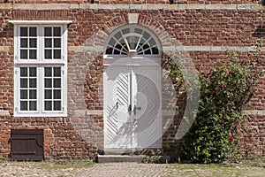 Front door, transom windows and climbing rose at a typical brick
