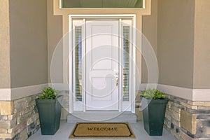 Front door with welcome mat and plants