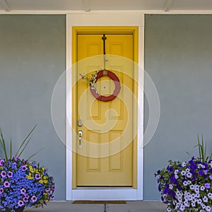 Front door with wreath and colorful potted flowers