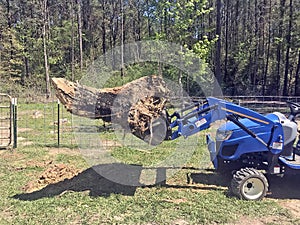 Front end loader hauling stump