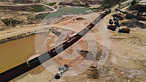 Front-end loader loading sand it to the freight train. Mining work in a quarry. Aerial view of an wheel loader load the minerals