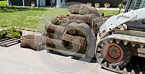 Front end loader and a pallet with rolls of sod grass for installation