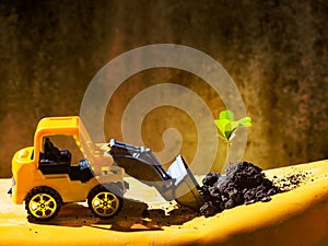 Front end loader truck toy scooping up green plant and earth on