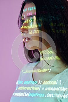 Front end programming language`s scripts. Beautiful young woman is in projector neon lights in the studio
