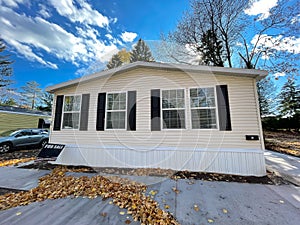 Front entrance view of brand new prefab mobile home with for sale yard sign post near Rochester, New York