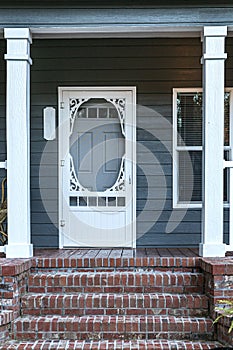 Front exterior door of a small blue gray mobile home with red brick steps