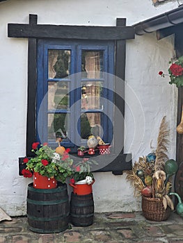 Front facade of a rural house with dark blue windows decorated with flowers and other decorations