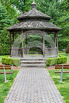 Front of gazebo with wooden benches and paver path.