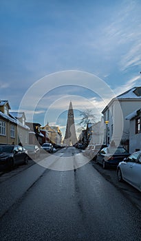 Front of Hallgrimskirkja church illuminated by the first light of dawn and lit street lamps from Skolavordustigur street icy with