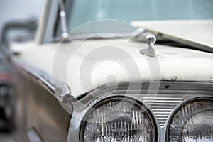 Front headlight of classic 1960s atutomobile ourside in sunshine