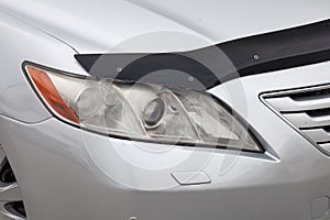 Front headlight view of car in silver color after cleaning and detailing with washer before sale.