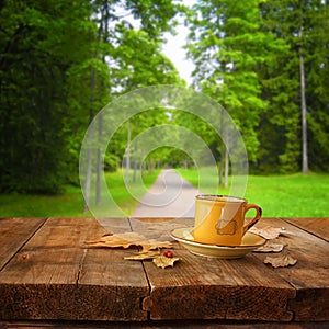 Front image of coffee cup over wooden table in front of forest background