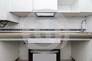 Front image Home kitchen with oak-colored wooden countertop, white furniture without handles and lack of hall for some appliances