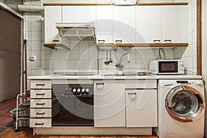Front image of kitchen furnished with antique white furniture with wooden handles, cabinet with multiple drawers, microwave oven