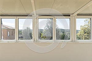 Front image of a wall with aluminum and glass windows with good views of the mountain with trees on a bright day