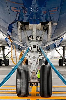 The front landing gear of the aircraft standing on the refueling at the airport.