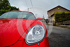 Front light of a red Porsche Cayman 2.7 sport car, parked in a