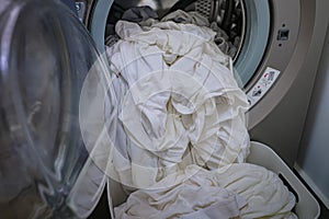 A front load washer with a pile of white clothings. photo