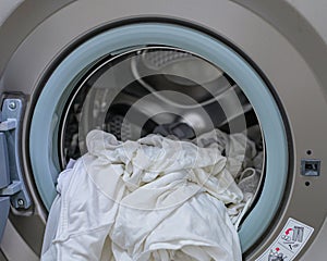 A front load washer with a pile of white clothings. photo