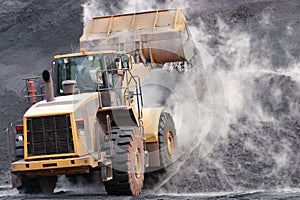 Front loader dumping mineral material on heap