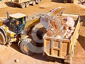 Front loader loads rock into a dump truck