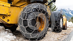 Front loader for snow removal with metal snow chains on wheels. Snow removal in the mountains.