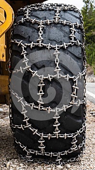 Front loader for snow removal with metal snow chains on wheels. Snow removal in the mountains.