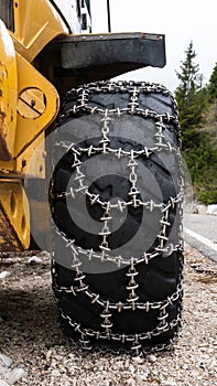 Front loader for snow removal with metal snow chains on wheels. Snow removal in the mountains.