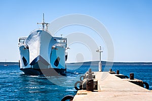 Front loading ferry boat moored with lifted bow at pier.