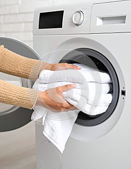 Woman taking clean clothes out of washing machine, closeup photo