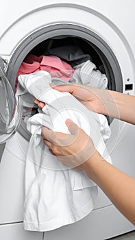 Woman taking clean clothes out of washing machine, closeup photo