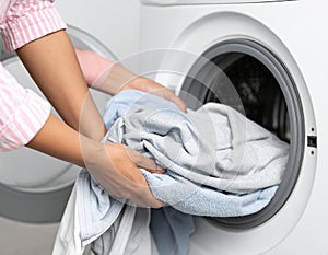 Woman taking clean clothes out of washing machine, closeup photo