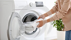Woman taking clean clothes out of washing machine, closeup photo