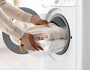 Woman taking clean clothes out of washing machine, closeup photo