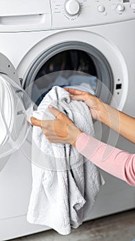 Woman taking clean clothes out of washing machine, closeup photo