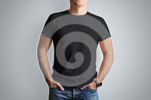 Front mockup black T-shirt on a young guy isolated on a gray ba